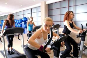 Women working out on spinning bikes at the gym photo