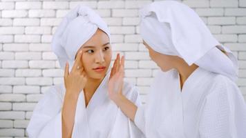 Two Asian girls in white bathrobes with towels on heads talking in living room. photo