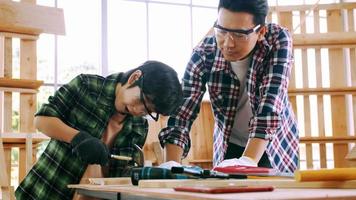 Young male carpenter teaching his son how to work with wood in workshop. photo