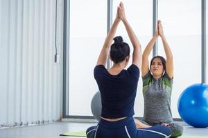 Two asian women doing yoga together at a gym. photo