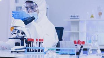 Scientist in PPE suite doing some research checking a liquid in a test tube at laboratory. photo