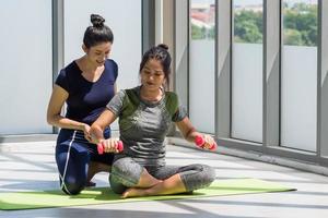 dos mujeres asiáticas haciendo yoga juntas en un gimnasio. foto