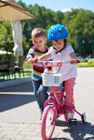 niño y niña en el parque aprendiendo a andar en bicicleta foto