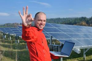 ingeniero que usa una computadora portátil en el campo de la planta de paneles solares foto