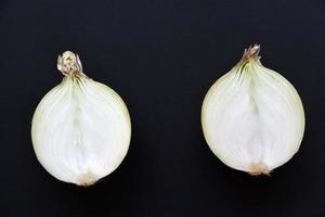 Onion cut in half and whole on a black background. Delicious bulbs close-up. photo