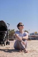 Young mother with sunglasses relaxing on beach photo