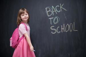 school girl child with backpack writing  chalkboard photo