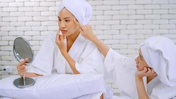 Two Asian girls in white bathrobes with towels on heads talking in living room. photo