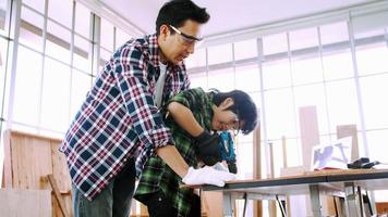 Young male carpenter teaching his son how to work with wood in workshop. photo