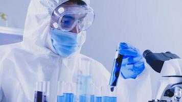 Scientist in PPE suite doing some research checking a liquid in a test tube at laboratory. photo