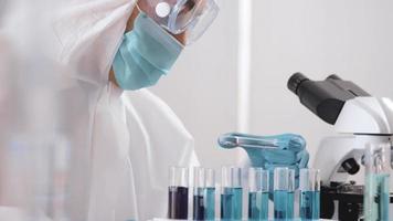 Scientist in PPE suite doing some research checking a liquid in a test tube at laboratory. photo