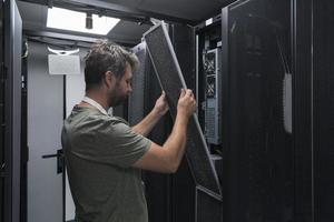 el ingeniero que trabaja en la sala de servidores o en el centro de datos, el técnico coloca en un rack un nuevo servidor de supercomputadora de mainframe de negocios corporativos o granja de minería de criptomonedas. foto