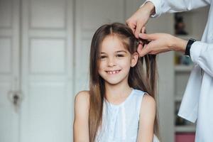 Mother braiding cheerful little girl photo