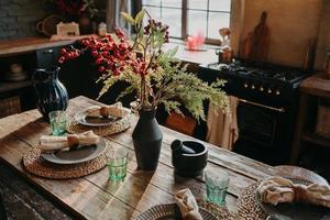 mesa de comedor muy bien decorada con platos, servilletas, jarrón. interior de fondo de cocina. concepto de restauración. estilo retro. diseño de interiores foto
