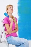 happy smiling woman painting interior of house photo