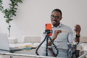 African american businessperson gives presentation for team online by video call using smartphone photo