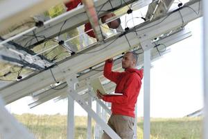 engineer using laptop at solar panels plant field photo