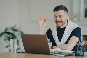 Happy businessman greeting colleague during video conference photo