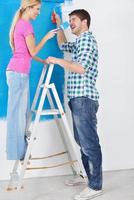 pareja feliz pintando una pared en su nuevo hogar foto