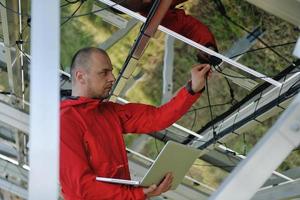 ingeniero que usa una computadora portátil en el campo de la planta de paneles solares foto