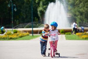 Boy and girl in park learning to ride a bike photo