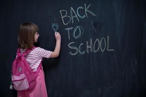 school girl child with backpack writing  chalkboard photo