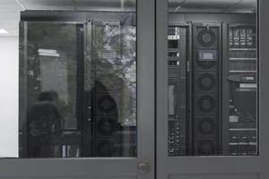 Software Engineer Working on a Laptop Computer in a Modern Server room. Monitoring Room Big Data Scientist in reflection of the entrance door. photo