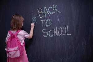 school girl child with backpack writing  chalkboard photo