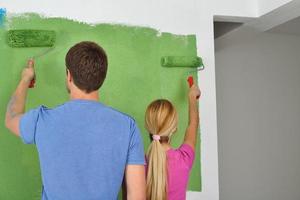 happy couple paint wall at new home photo