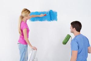 pareja feliz pintando una pared en su nuevo hogar foto