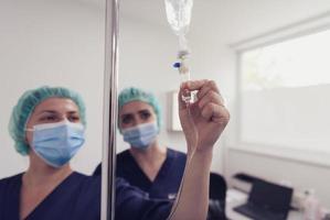 General practitioner holding intravenous drip infusion. Doctor handling IV fluid drip with copy space on white background. Nurse performing Intravenous therapy. photo