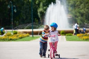 Boy and girl in park learning to ride a bike photo