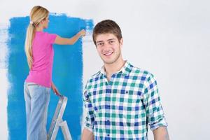 happy couple paint wall at new home photo