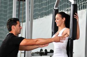 woman in the fitness gim working out with personal trainer photo