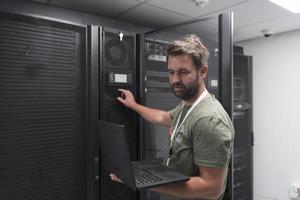 Data Center Engineer Using Laptop Computer Server Room Specialist Facility with Male System Administrator Working with Data Protection Network for Cyber Security or Cryptocurrency Mining Farm. photo