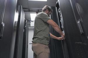 el ingeniero que trabaja en la sala de servidores o en el centro de datos, el técnico coloca en un rack un nuevo servidor de supercomputadora de mainframe de negocios corporativos o granja de minería de criptomonedas. foto