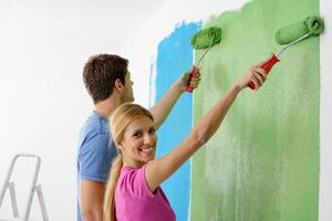 pareja feliz pintando una pared en su nuevo hogar foto