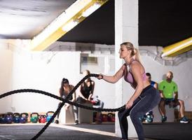 athlete woman doing battle ropes cross fitness exercise photo