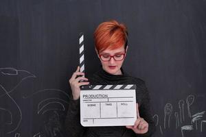 redhead woman holding clapper on black background photo