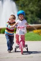 Boy and girl in park learning to ride a bike photo