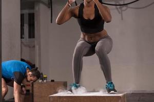 black woman is performing box jumps at gym photo