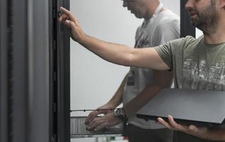 Technicians team updating hardware inspecting system performance in super computer server room or cryptocurrency mining farm. photo