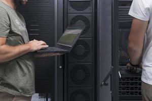 Data Center Engineer Using Laptop Computer. Server Room Specialist Facility with Korean Male System Administrator Working with Data Protection Network for Cyber Security. photo