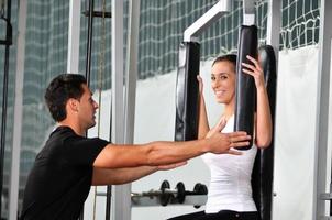 woman in the fitness gim working out with personal trainer photo