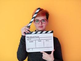 redhead woman holding movie  clapper on yellow background photo