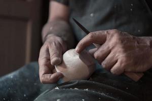 Manos tallando copa de madera, trabajando con cincel de cerca. taller de madera. proceso de fabricación de utensilios de cocina de madera foto