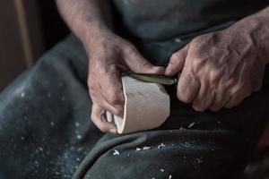 Manos tallando copa de madera, trabajando con cincel de cerca. taller de madera. proceso de fabricación de utensilios de cocina de madera foto