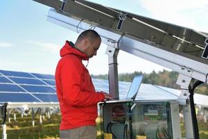 engineer using laptop at solar panels plant field photo