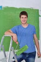 handsome young man paint white wall in color photo