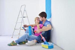 pareja joven feliz relajándose después de pintar en un nuevo hogar foto